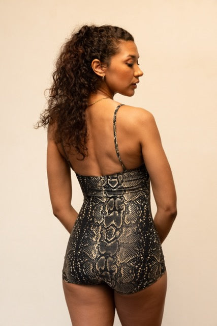 Woman wearing a black lace romper against a beige background