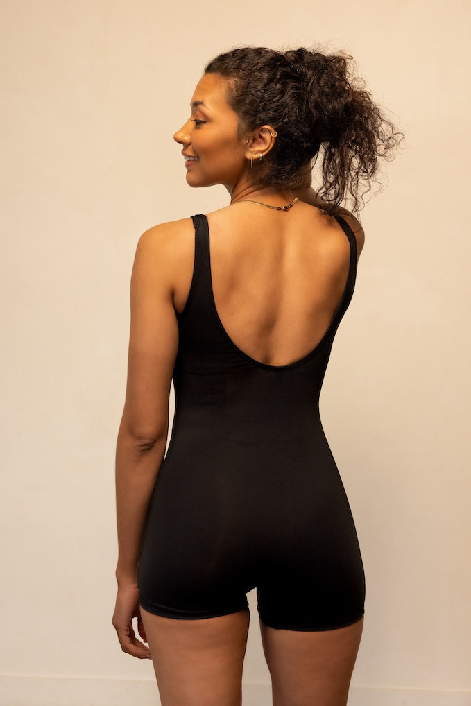 Woman wearing a black bodysuit against a plain background
