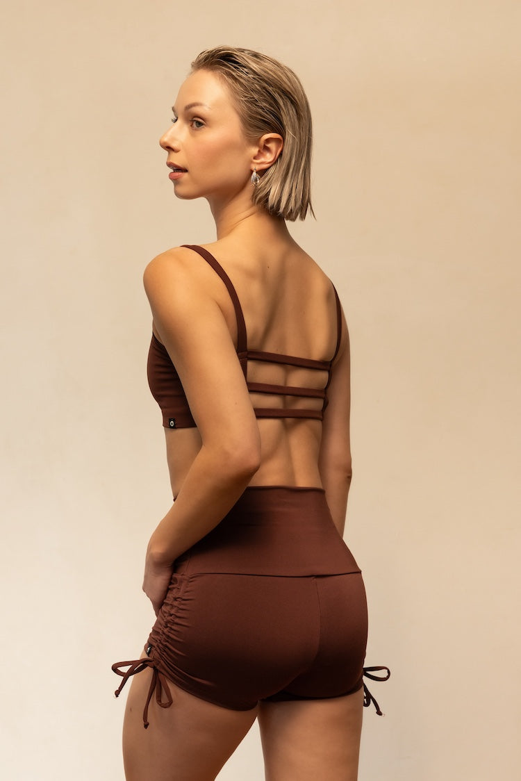 Woman wearing a brown swimsuit with a beige background