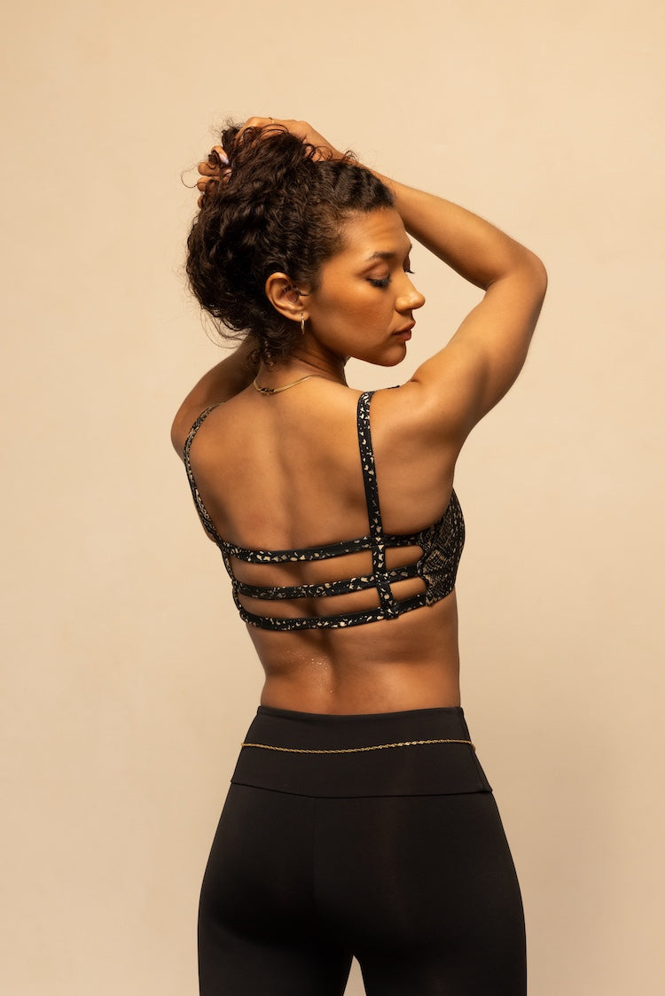 Woman wearing a black strappy top and leggings against a beige background