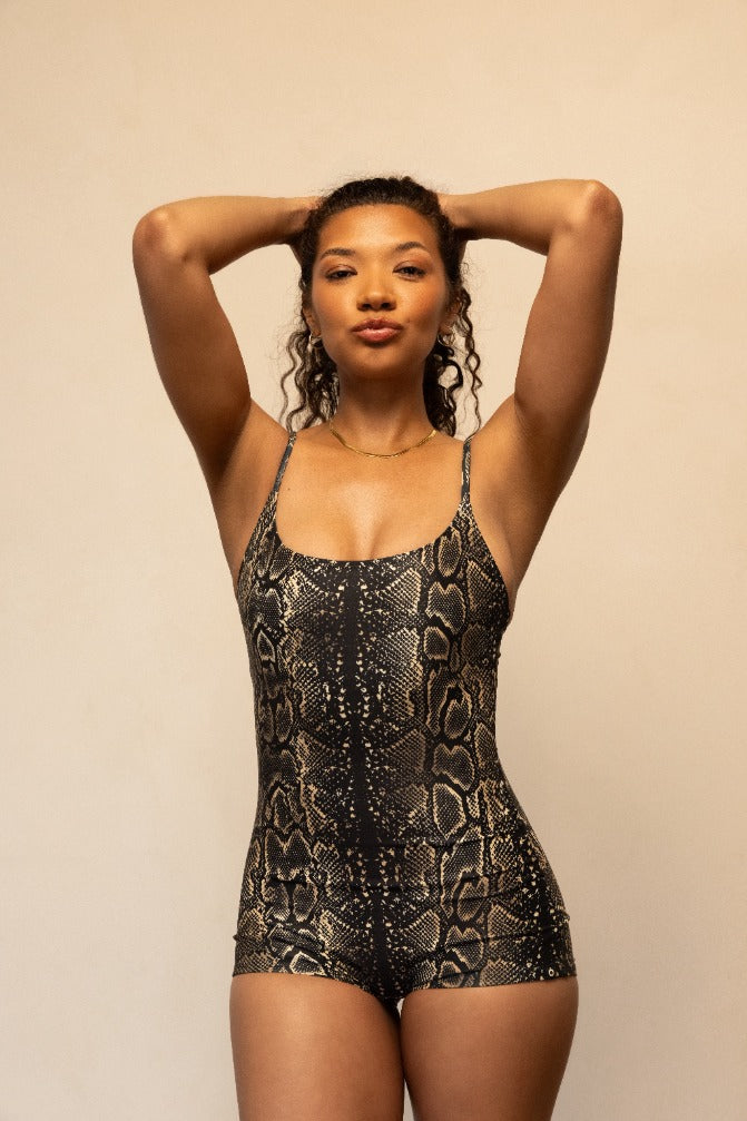 Woman wearing a black snake print bodysuit against a beige background