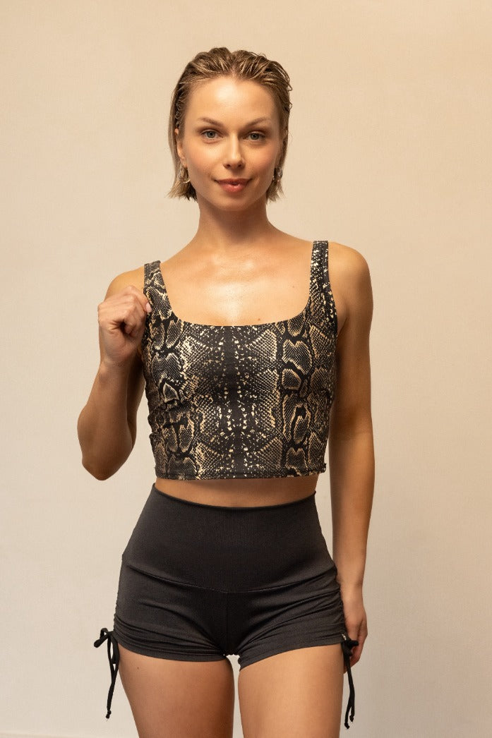 Woman wearing a patterned crop top and black shorts on a beige background