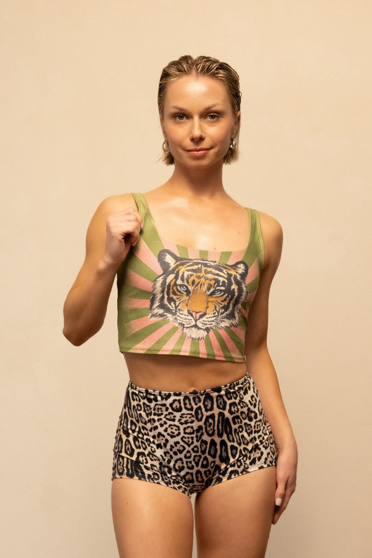 Woman wearing a crop top with a tiger design and leopard print shorts on a beige background