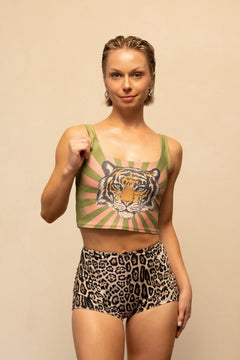 Woman wearing a crop top with a tiger design and leopard print shorts on a beige background
