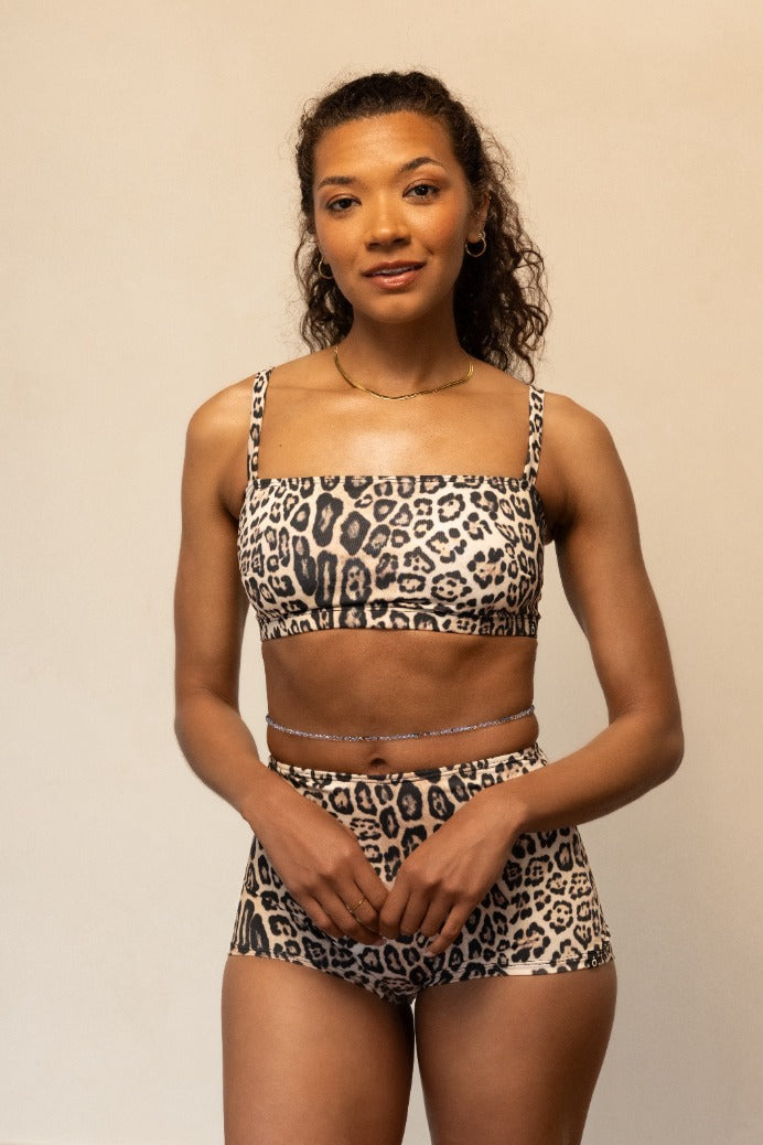 Woman wearing a leopard print bikini set against a plain background